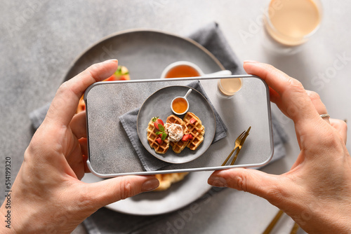 Woman take a photo out breakfast of croffles and coffee with by smartphone. Close up. photo