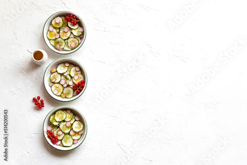 Radish and cucumber salad served in a three small round bowls in a row