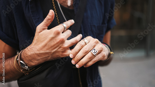 Close-up of male hands in bracelets and rings. Man adjusts the ring on his finger. Guy twists the ring on his finger