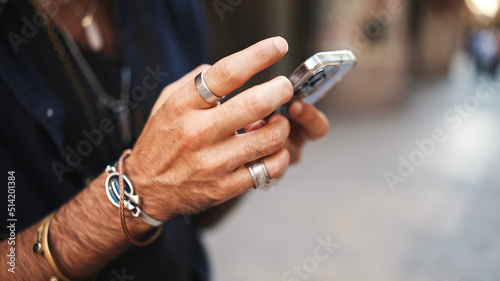 Close-up of male hands in bracelets and rings. Man is using mobile phone. Guy writes message on his smartphone,