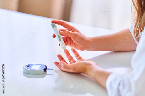 Female using lanceter on finger for measuring and checking blood glucose level. Healthcare and mellitus diabetes treatment photo