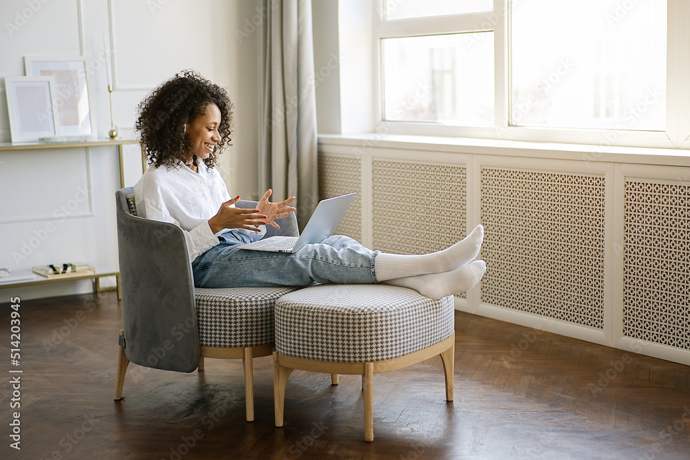 Portrait Beautiful young african american girl sitting in the living room and having a video chat through tablet. Remote Work, Home Office Concept Portrait Beautiful young african american girl sitting in the living room and having a video chat through tablet. Remote Work, Home Office Concept