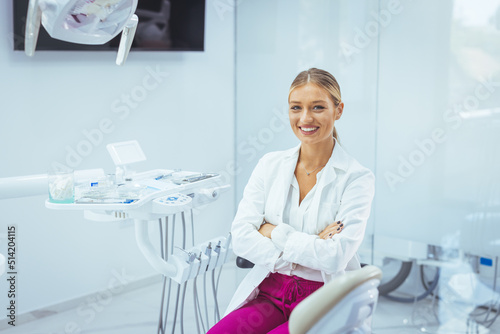 Portrait of a Caucasian woman dentist, sitting in her office next to a dentist chair, smiling. Portrait of female dentist. She standing at her office. Healthcare and medicine concept