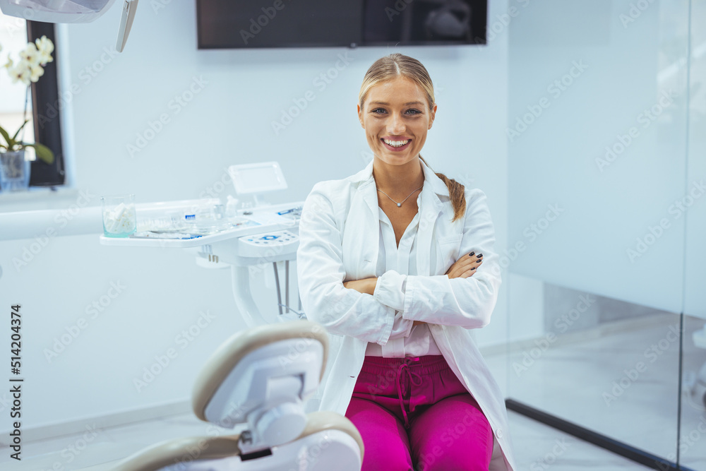 Fototapeta premium People, medicine, stomatology and healthcare concept - happy young female dentist with tools over medical office background. Portrait of female dentist smiling with arms crossed in dental clinic