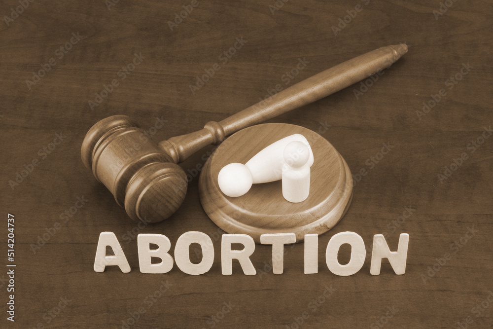 Letters abortion with judge gavel and figures of female and child. Letters abortion with judge gavel and figures of female and child.