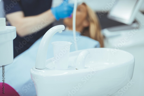 Smiling pretty woman looking with trust at dentist doctor during treatment. Beautiful young woman doing tooth examination in the dental office. Portrait of smiling girl on a dental chair in dentistry