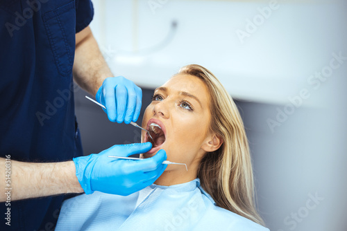 European young woman sitting in medical chair while dentist fixing her teeth at dental clinic. Dentist examining a patient s teeth in the dentist. The woman came to see the dentist.