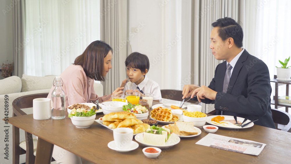 Portrait of happy smiling Asian Family eating breakfast food together before the child going to school at home. Family relationship. Love of father, mother, and son. People lifestyle. Business man.