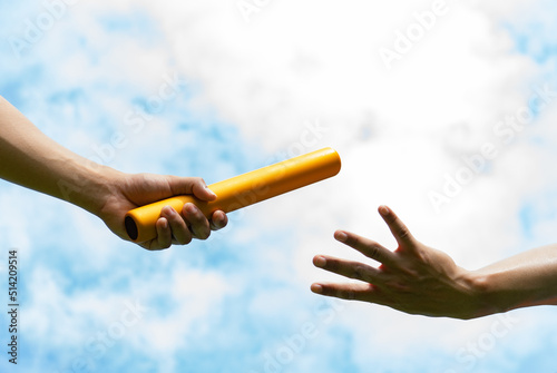 Close up hand set baton from hand to hand on sky background. Business concept for teamwork and team builder.