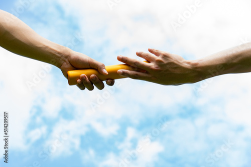 Close up hand set baton from hand to hand on sky background. Business concept for teamwork and team builder.