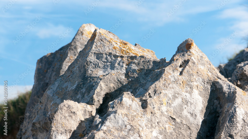 Rocas graniticas con manchas de liquen amarillo en el litoral bajo cielo azul Rocas graniticas con manchas de liquen amarillo en el litoral bajo cielo azul