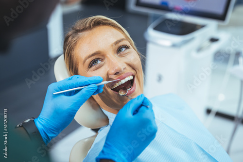 Dentist and patient in dentist office. Over the shoulder view of a dentist examining a patients teeth in dental clinic. Female having her teeth examined by a dentist.