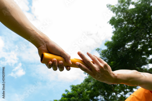 Close up hand set baton from hand to hand on sky background. Business concept for teamwork and team builder.