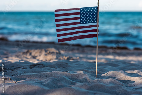 There is an American flag on the beach on the sand. A symbol of freedom. Patriotism. July 4th Holiday. Soft focus