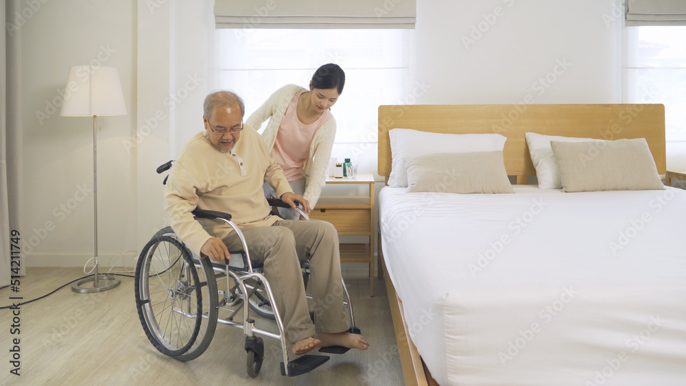 Asian woman nurse, daughter help father to get up from bed to wheelchair, supporting old senior elderly patient in bedroom in home or house in healthcare. People lifestyle. Family disability therapy. Asian woman nurse, daughter help father to get up from bed to wheelchair, supporting old senior elderly patient in bedroom in home or house in healthcare. People lifestyle. Family disability therapy.