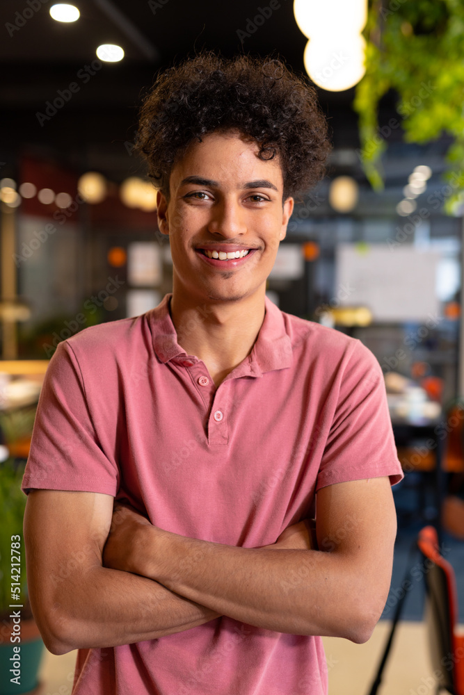 Portrait of smiling biracial young businessman standing with arms crossed in creative office Portrait of smiling biracial young businessman standing with arms crossed in creative office