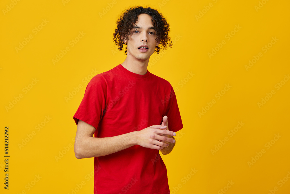 Joyful lovely funny Caucasian young man in red t-shirt posing isolated on over yellow studio background. The best offer with free place for advertising. Emotions for everyday concept