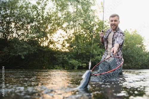 Fisherman catches a trout on the river in summer