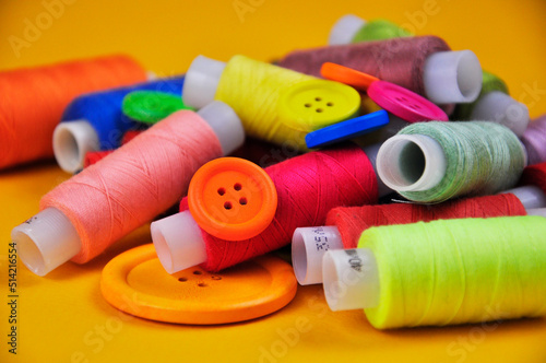 Set of multicolored buttons and Spools threads on a yellow background. Blurring.