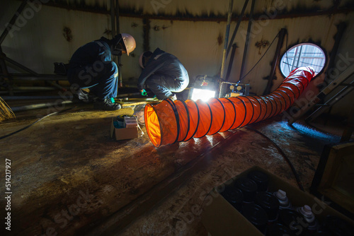 Male worker inspection vacuum test bottom plate tank with the area confined space blower air