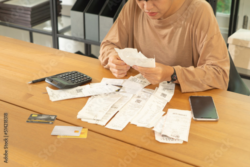 Portrait of stressed Asian woman, audit person and confused by calculate expense from invoice or receipt bills debt. No money to pay, mortgage or loan,bankruptcy at home.People lifestyle
