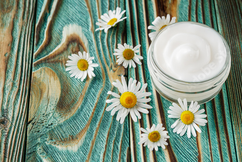 Chamomile cream in glass jar on the wooden background