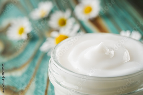 Chamomile cream in glass jar on the wooden background