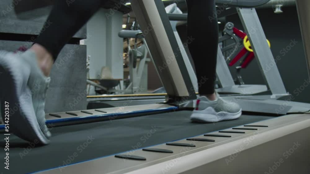 Back down view of woman energetic walk to warm up on treadmill close up Back down view of woman energetic walk to warm up on treadmill close up