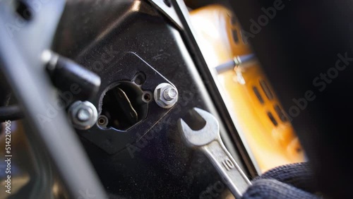 Unscrewing the carburetor mount with an open-end wrench. Close-up of unscrewing a nut on a gasoline power generator