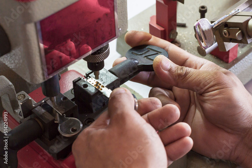Locksmith in workshop makes new key. Professional making key in locksmith. Machine production of duplicate metal key.