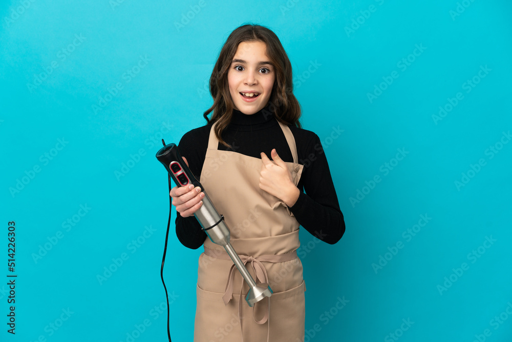 Little girl using hand blender isolated on blue background with surprise facial expression Little girl using hand blender isolated on blue background with surprise facial expression