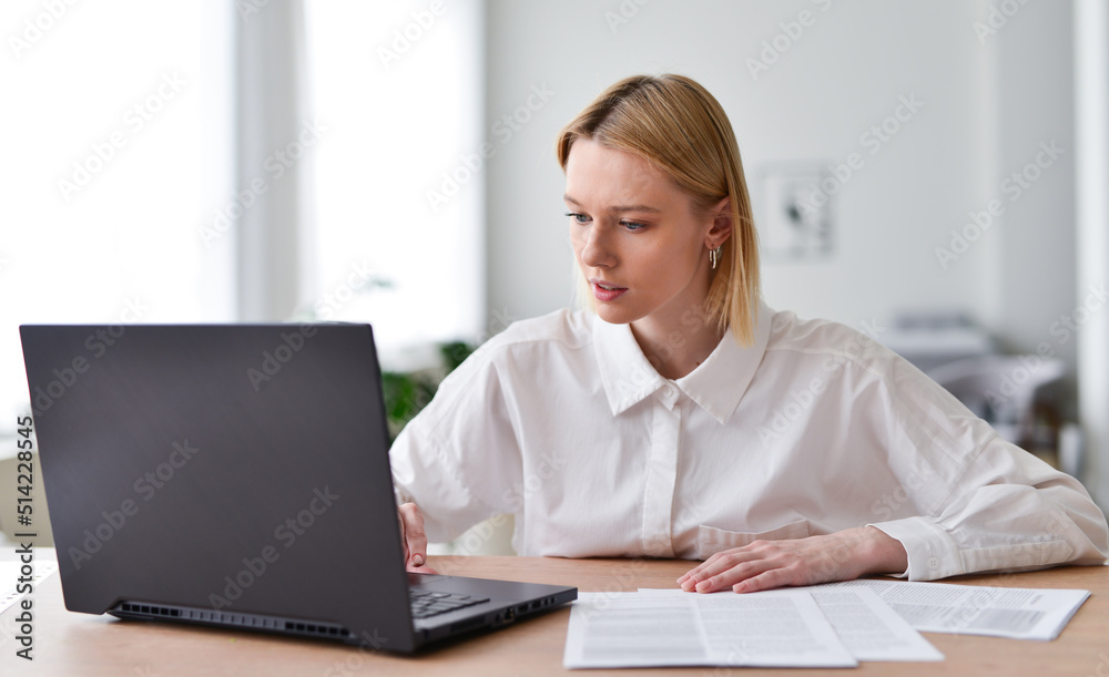 Young woman working on laptop in living room. Young woman working on laptop in living room.