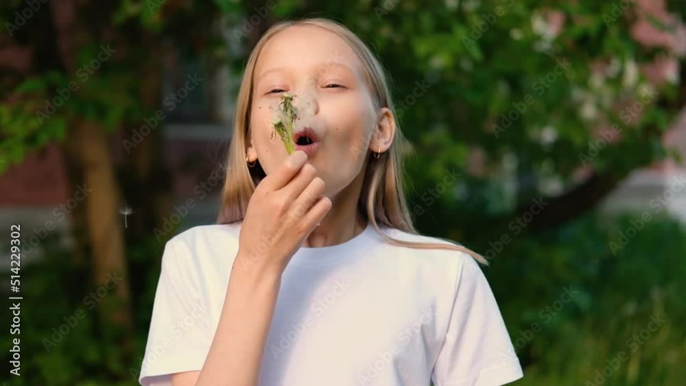 Blonde little girl blowing dandelion and smiling outdoor. Happy child enjoying summer holdidays. Allergy concept Blonde little girl blowing dandelion and smiling outdoor. Happy child enjoying summer holdidays. Allergy concept