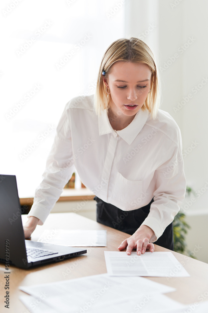 Woman standing at her desk looking at her papers Woman standing at her desk looking at her papers