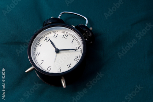 clock on bed with green quilt