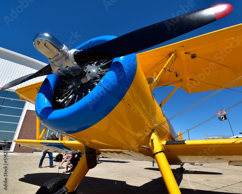A wide angle view of a colorful biplane at an airshow.