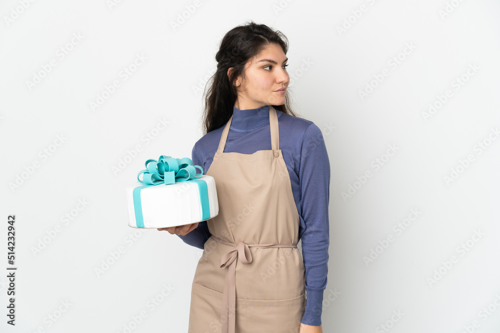 Pastry Russian chef holding a big cake isolated on white background looking to the side Pastry Russian chef holding a big cake isolated on white background looking to the side