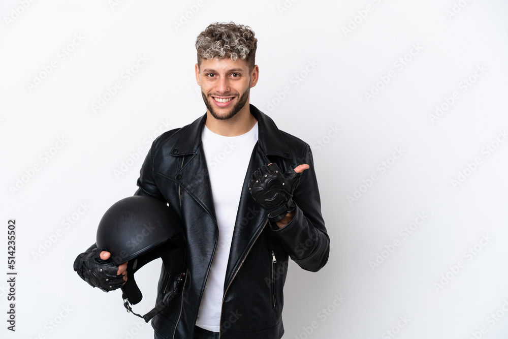 Young man with a motorcycle helmet isolated on white background pointing to the side to present a product Young man with a motorcycle helmet isolated on white background pointing to the side to present a product