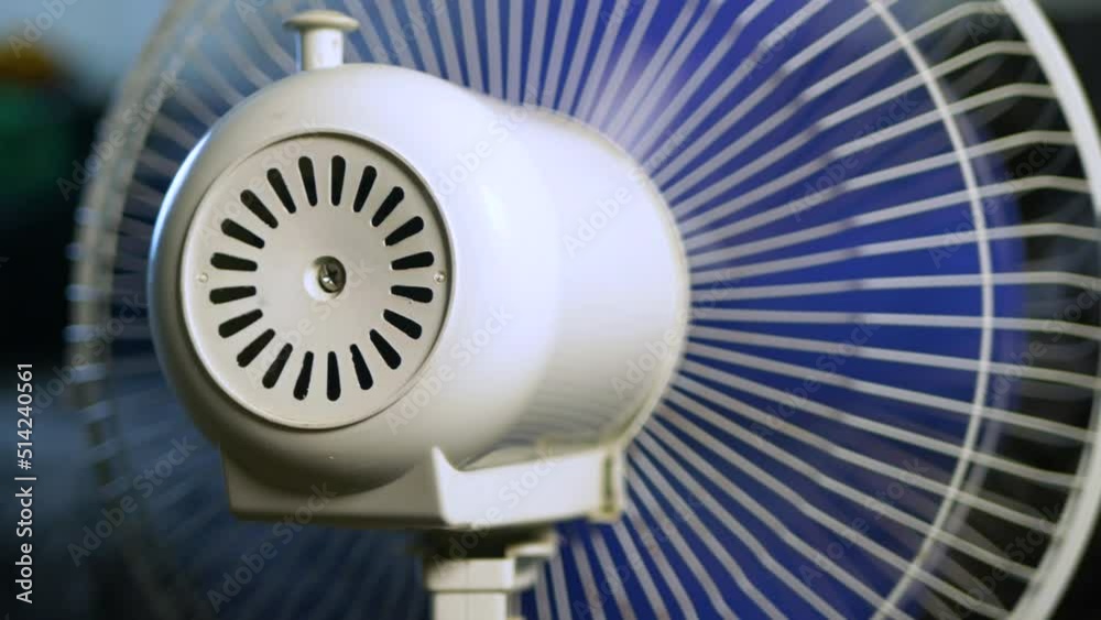 A fan with blue blades blows a room on a hot summer day A fan with blue blades blows a room on a hot summer day