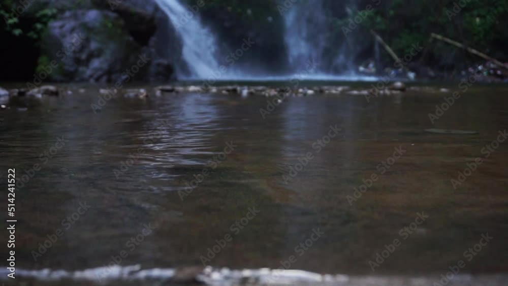 clear wavy water surface with waterfall on the background in the middle of Indonesia forest. clean water is a source of biological life.