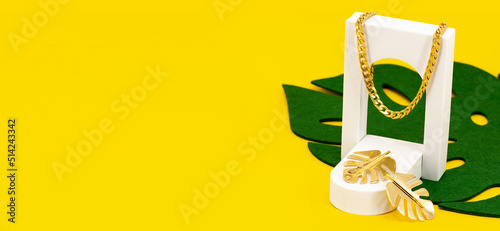 Złota biżuteria na zielonym liściu i żółtym tle - słoneczna ekspozycja złotych dekoracji w eleganckim stylu