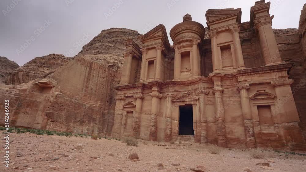 Ad Deir - Monastery - ruins carved in rocky wall at Petra Jordan, mountainous terrain with overcast sky background Ad Deir - Monastery - ruins carved in rocky wall at Petra Jordan, mountainous terrain with overcast sky background