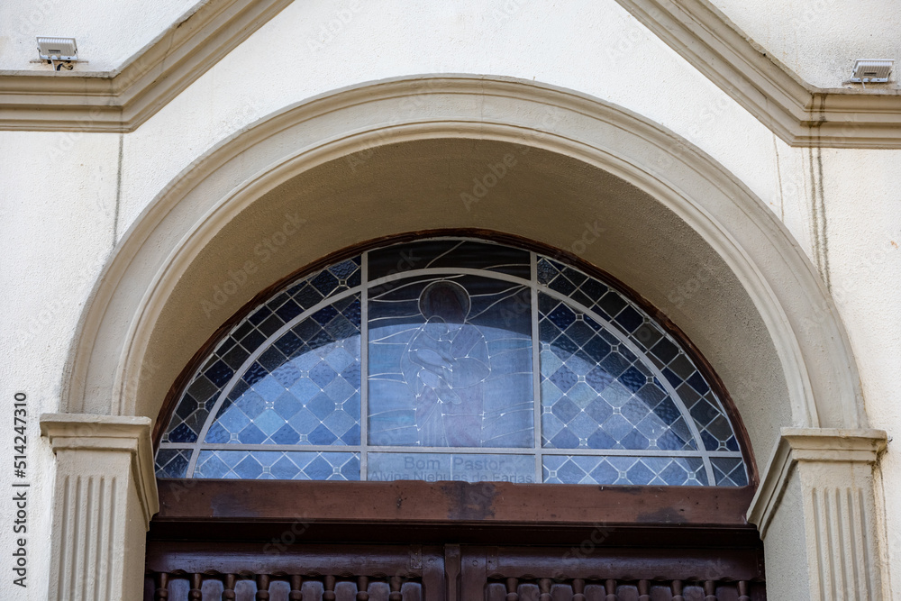 Stained glass windows on the facade of the Catholic church. Colored glass in the windows. Images of Jesus Christ on glass. Religious symbols of Christianity.