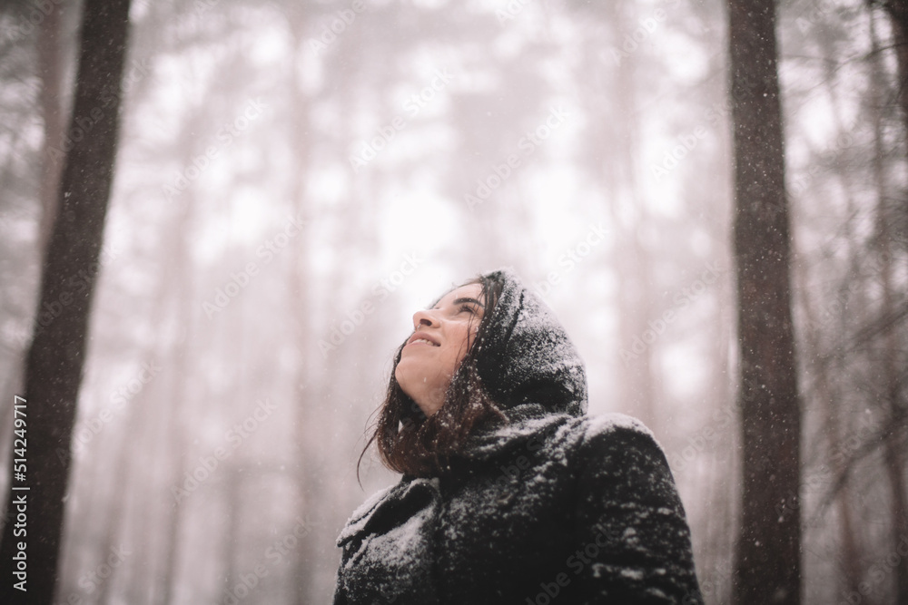 Portrait of happy young woman standing in forest during snowfall Portrait of happy young woman standing in forest during snowfall