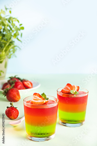 Glasses of tasty summer dessert layered colorful jelly with fresh strawberries