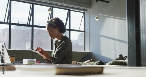 African american businesswoman sitting at table and using smartphone at office photo