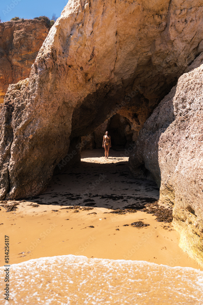 Carefree woman standing in cave on sandy beach