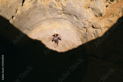 woman standing in rocky cave with hole in summer