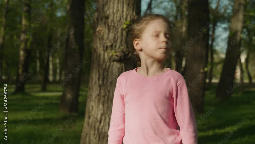 Funny little girl shakes head and waves stick in spring park closeup. Joyful child has fun grimacing in green garden. Active playing outdoor Funny little girl shakes head and waves stick in spring park closeup. Joyful child has fun grimacing in green garden. Active playing outdoor