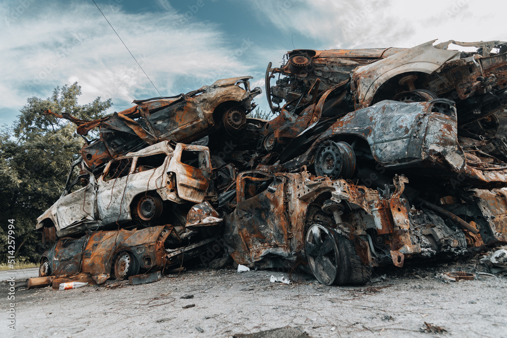 Fototapeta premium BUCHA, UKRAINE 22.06.2022 Irpin, Bucha. Car cemetery. Cars destroyed as a result of the war. A mountain of cars burned.